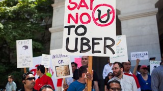 People hold up signs stating to reject Uber