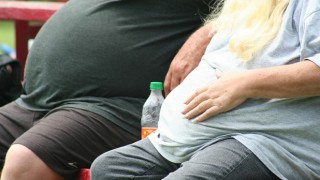 Two people suffering from obesity sit on a bench