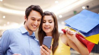 A man and woman look at their phone to see if they can find any top holiday apps