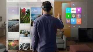 A man is using a Microsoft HoloLens to engage in virtual reality