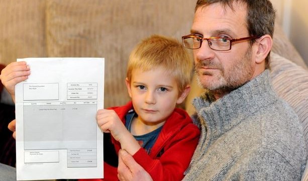 A five year old boy and his father pose with the invoice they received for his failure to attend a birthday party