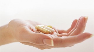 A woman's hand holds a bunch of pills dietary supplements