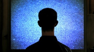 Male sitting before snow-filled TV