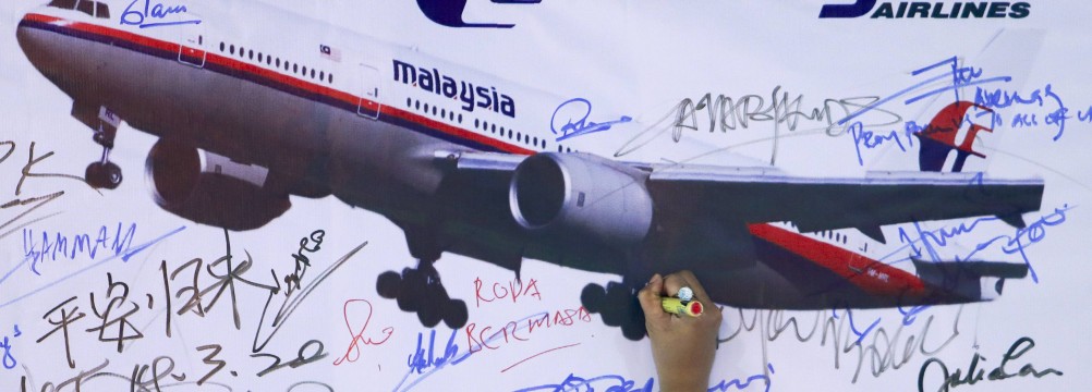 A woman writes on the memorial wall of MH370